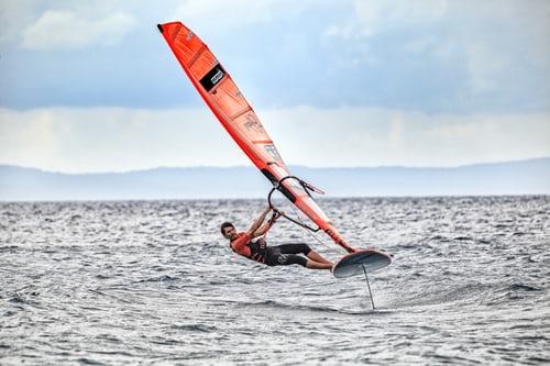 profesjonalny windsurfer łapie wiatr w żagiel i trenuje na otwartym morzu